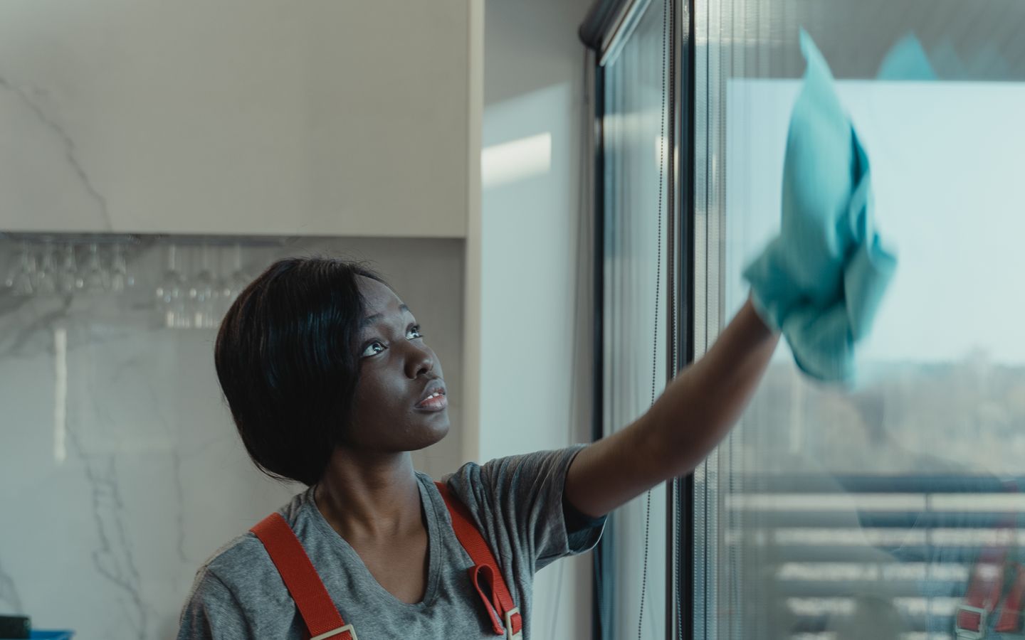 Professional cleaner polishing a large window inside a luxury home